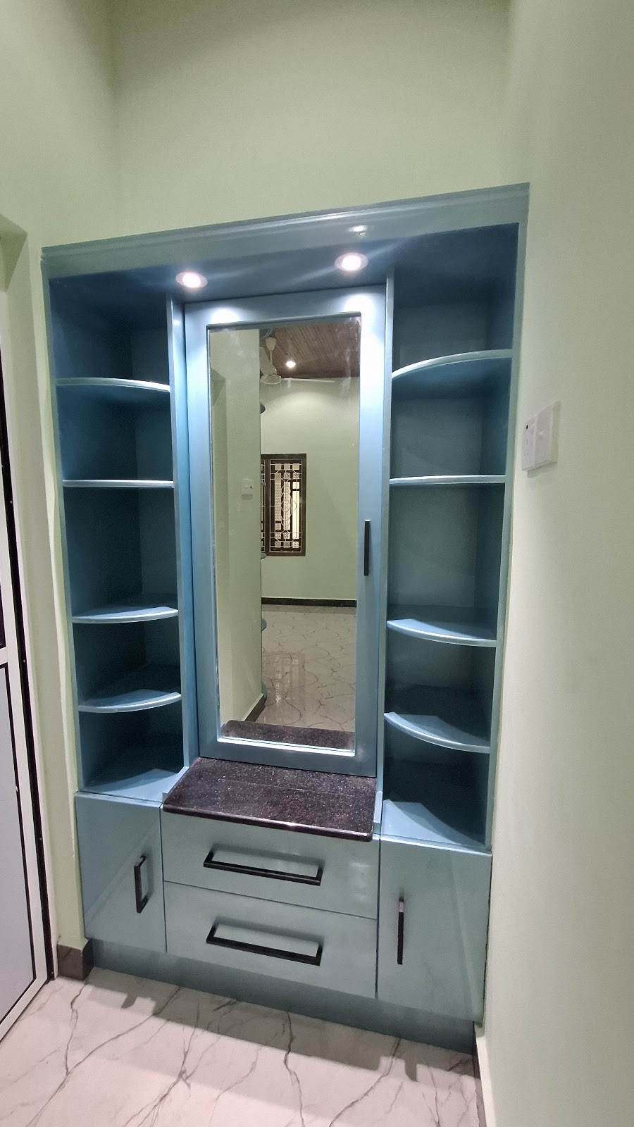Illuminated dressing mirror with teal shelves and lower drawers
