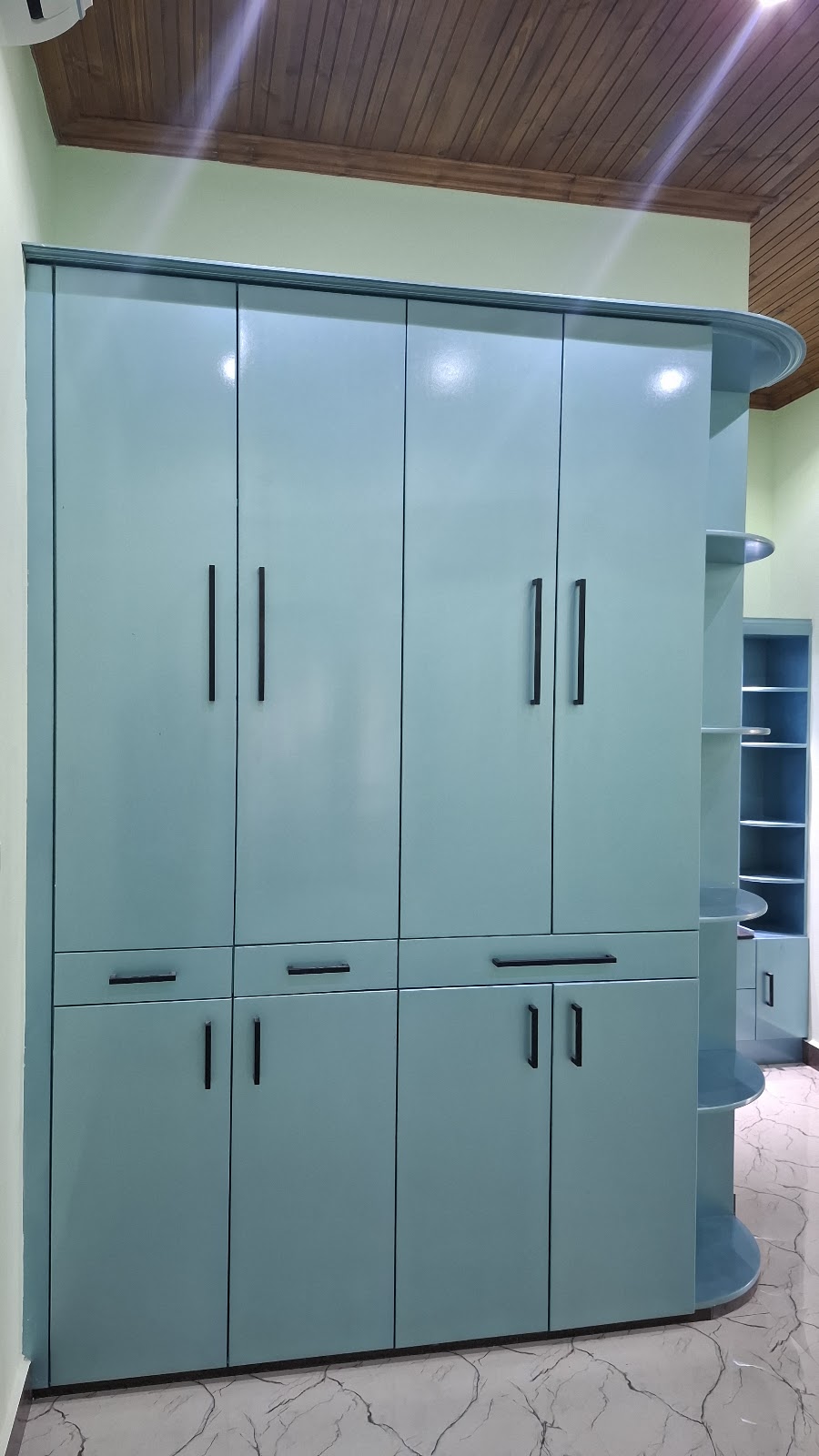Front view of a teal wardrobe with drawers and curved open shelves