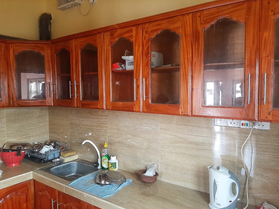 Full view of overhead glazed timber kitchen cupboards, tiled splashback, and stainless steel sink
