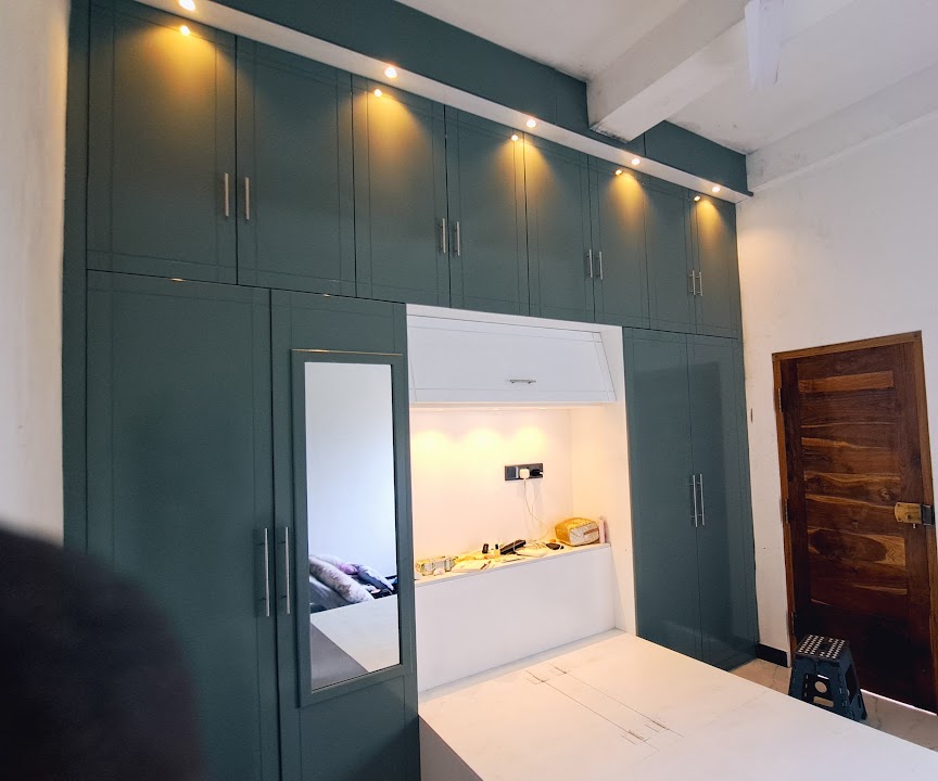 Dark green fitted wardrobe with a mirror and open central niche