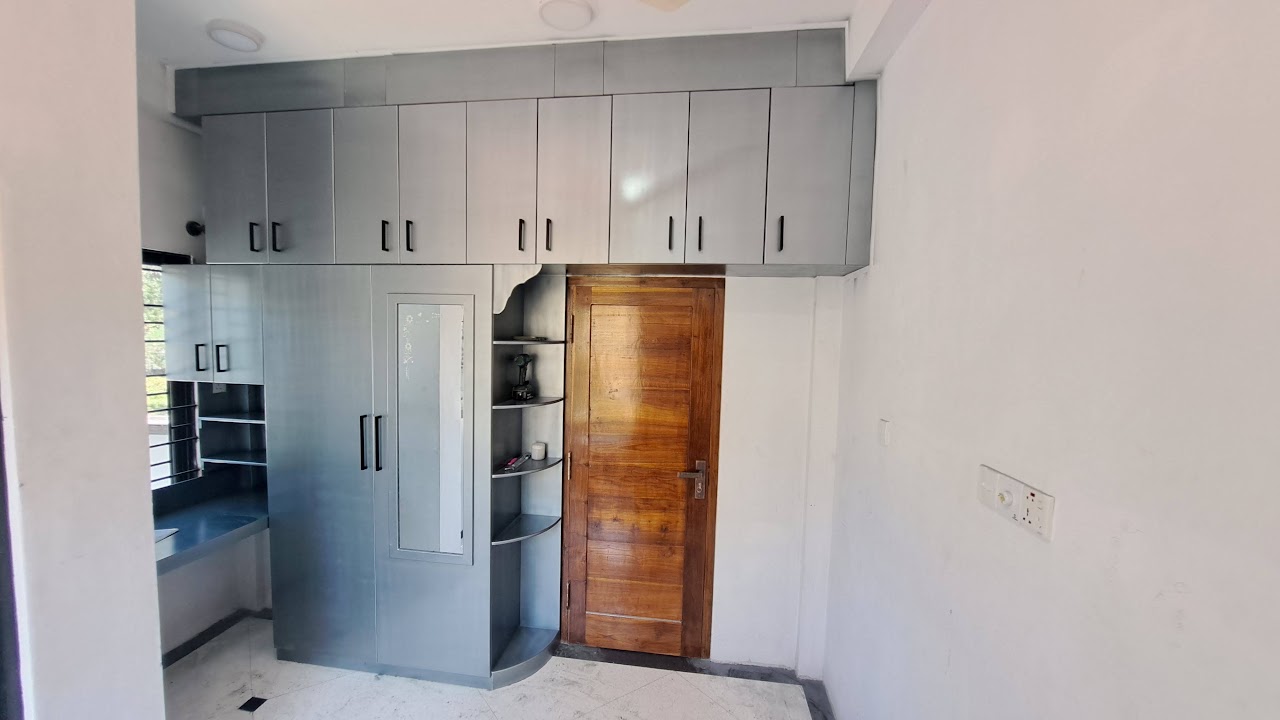 Full-height grey fitted cabinets with a vertical mirror and open corner shelves