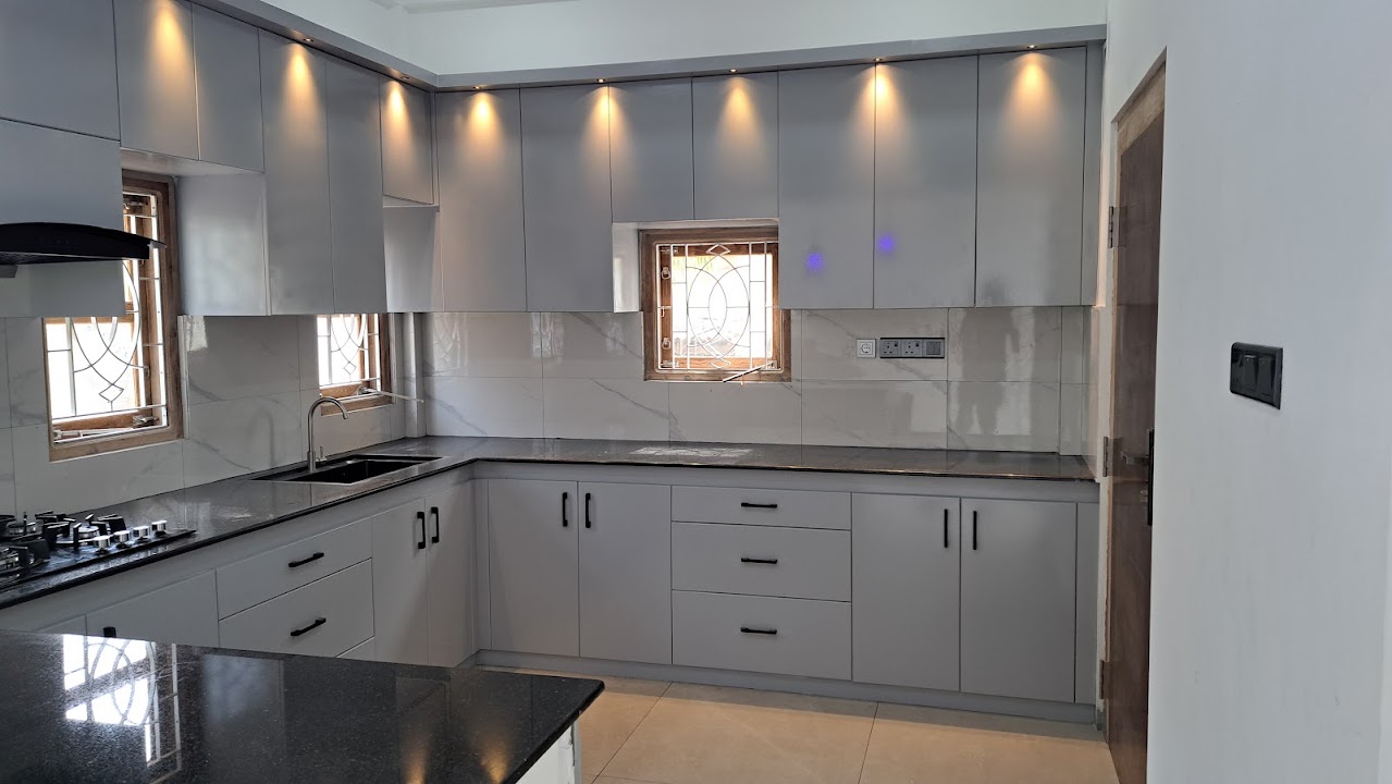 Fitted contemporary grey kitchen with ceiling downlights, black granite countertops, and tiled walls