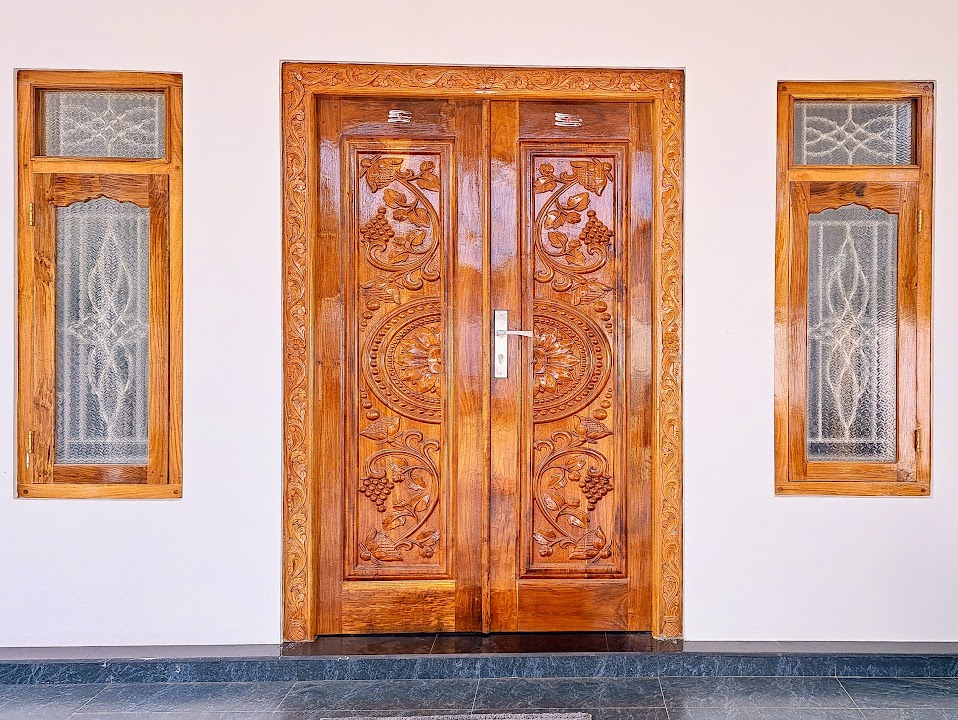 Carved paired timber doors with circular centre motifs and narrow textured-glass sidelights