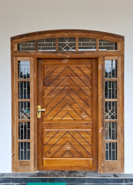 Solid timber entrance door with chevron grooves, geometric sidelights, and an arched transom