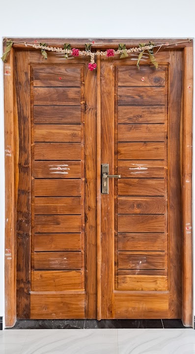 Full front vertical view of horizontal grooved double door with festival toran garland