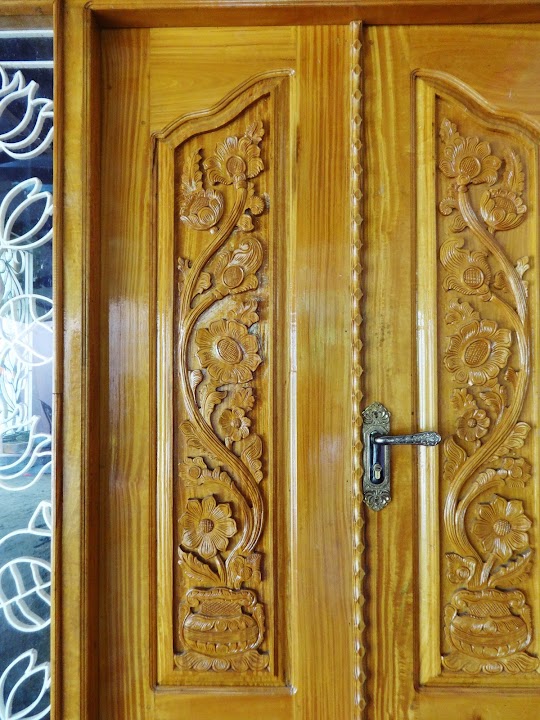 Carved paired timber entrance doors with relief-carved floral vines rising from decorative urns