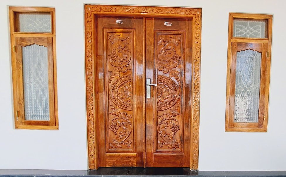 Carved paired timber doors with circular centre motifs and narrow textured-glass sidelights