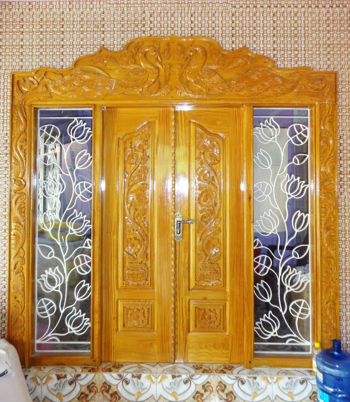 Polished carved double entrance with an ornate crown and floral metalwork sidelights