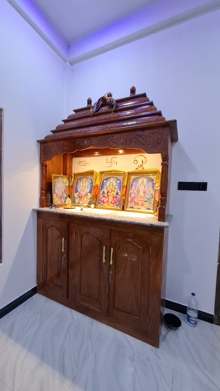 Freestanding timber pooja cabinet with carved crown and illuminated shrine shelf
