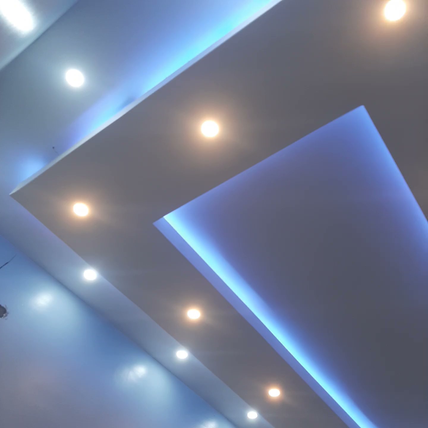 Layered floating gypsum tray ceiling with blue concealed lighting and recessed downlights