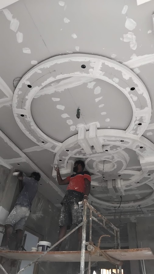 Inpalakan craftsmen on scaffolding applying jointing compound and plaster