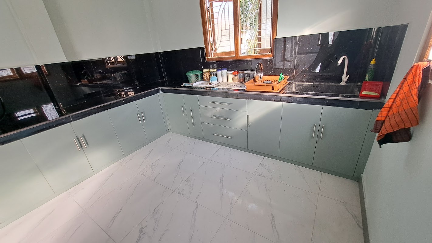 L-shaped polished granite kitchen counter with undermount double sink and matching overhead cabinets