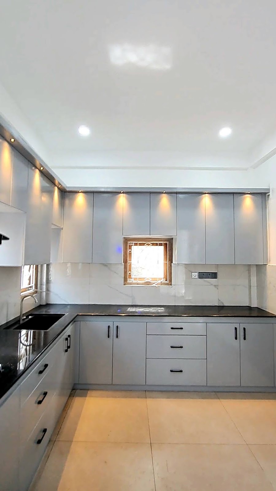 Completed soft grey fitted kitchen with black worktops and warm display lighting