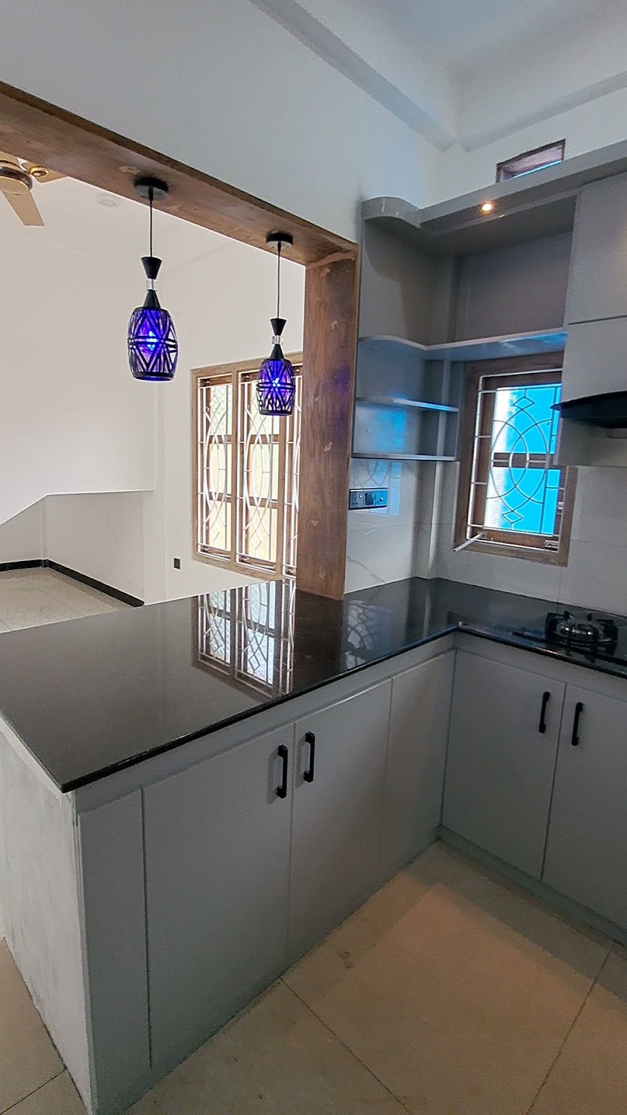 Grey base cabinets and dark counter beneath pendant lights