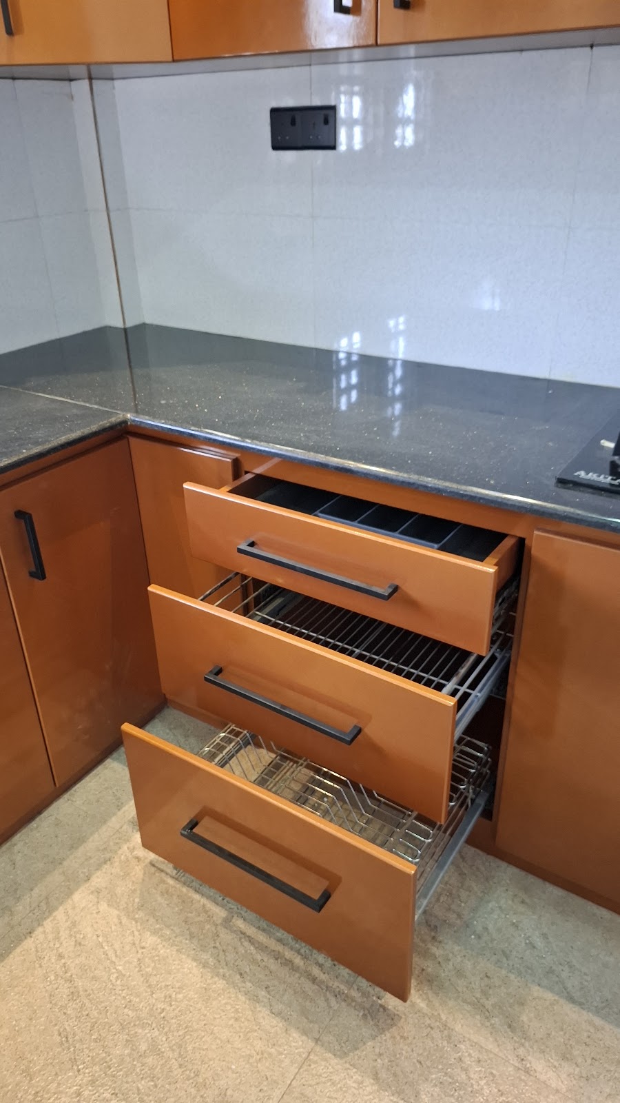 Open pull-out drawers below the dark kitchen worktop