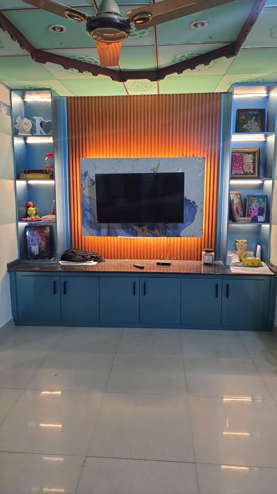 Teal television feature wall with rounded display towers and illuminated timber slats