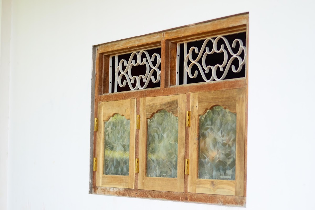 Three-sash timber casement window with textured glass and wrought iron transom