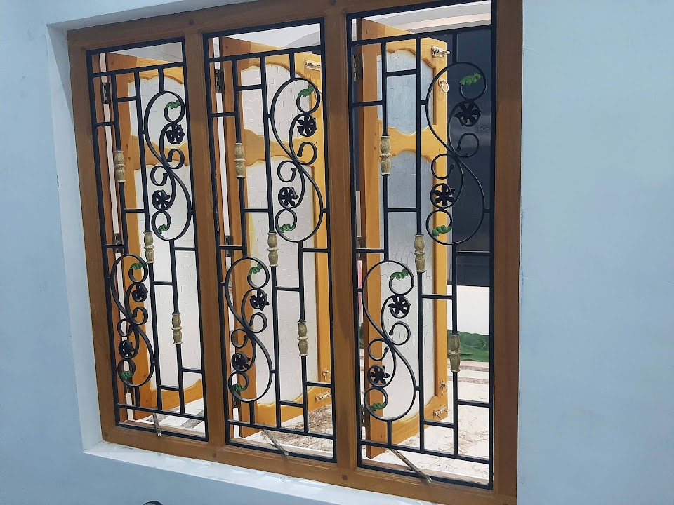 Timber-framed three-section window with decorative dark metal scroll grilles