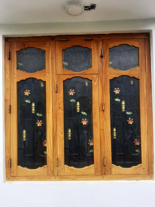 Three-section timber window with scalloped arches and decorative floral metal grilles