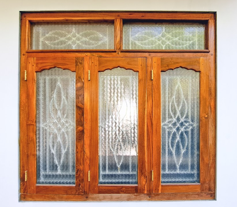 Three-section timber window with arched details and textured glass above and below