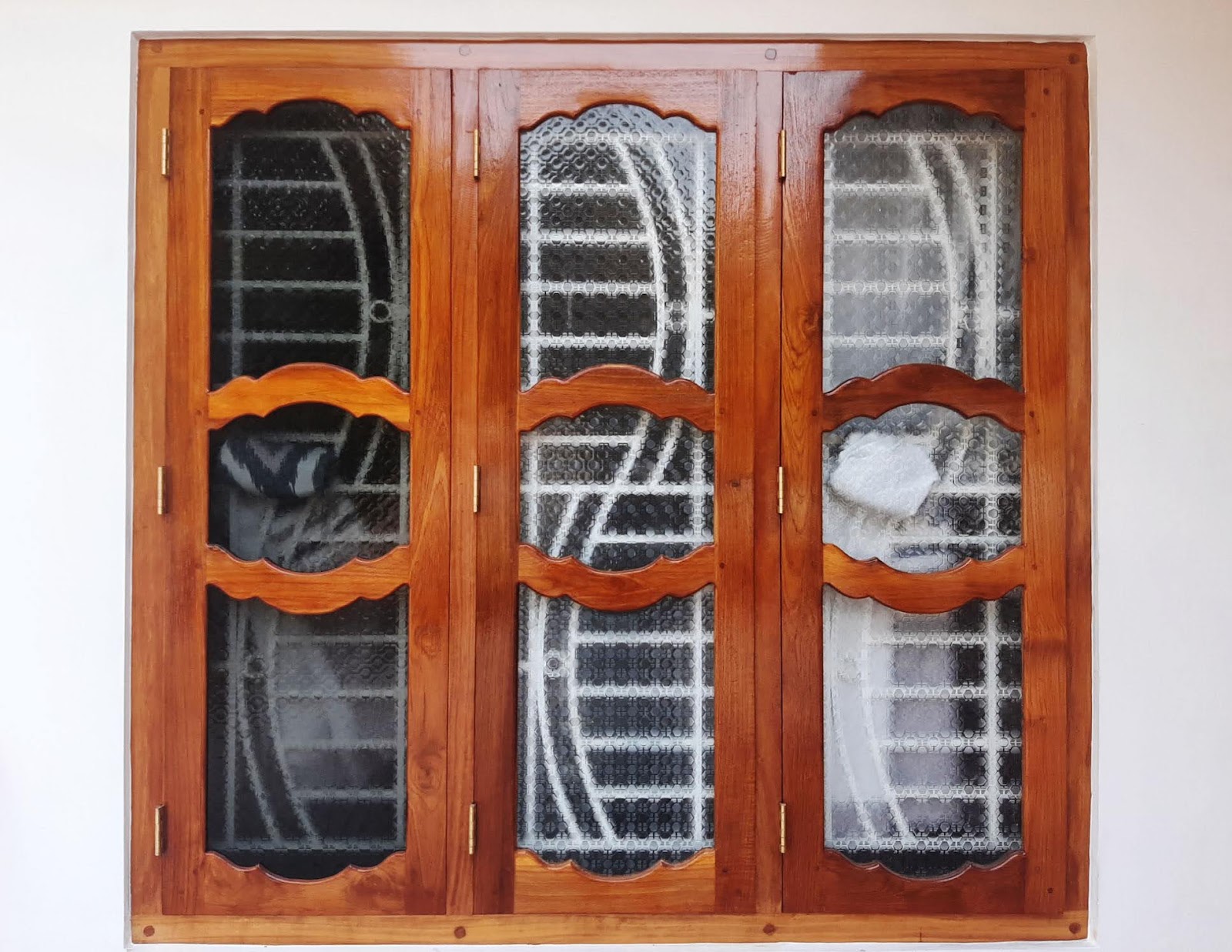 Three-leaf timber window with curved rails and decorative metal grilles