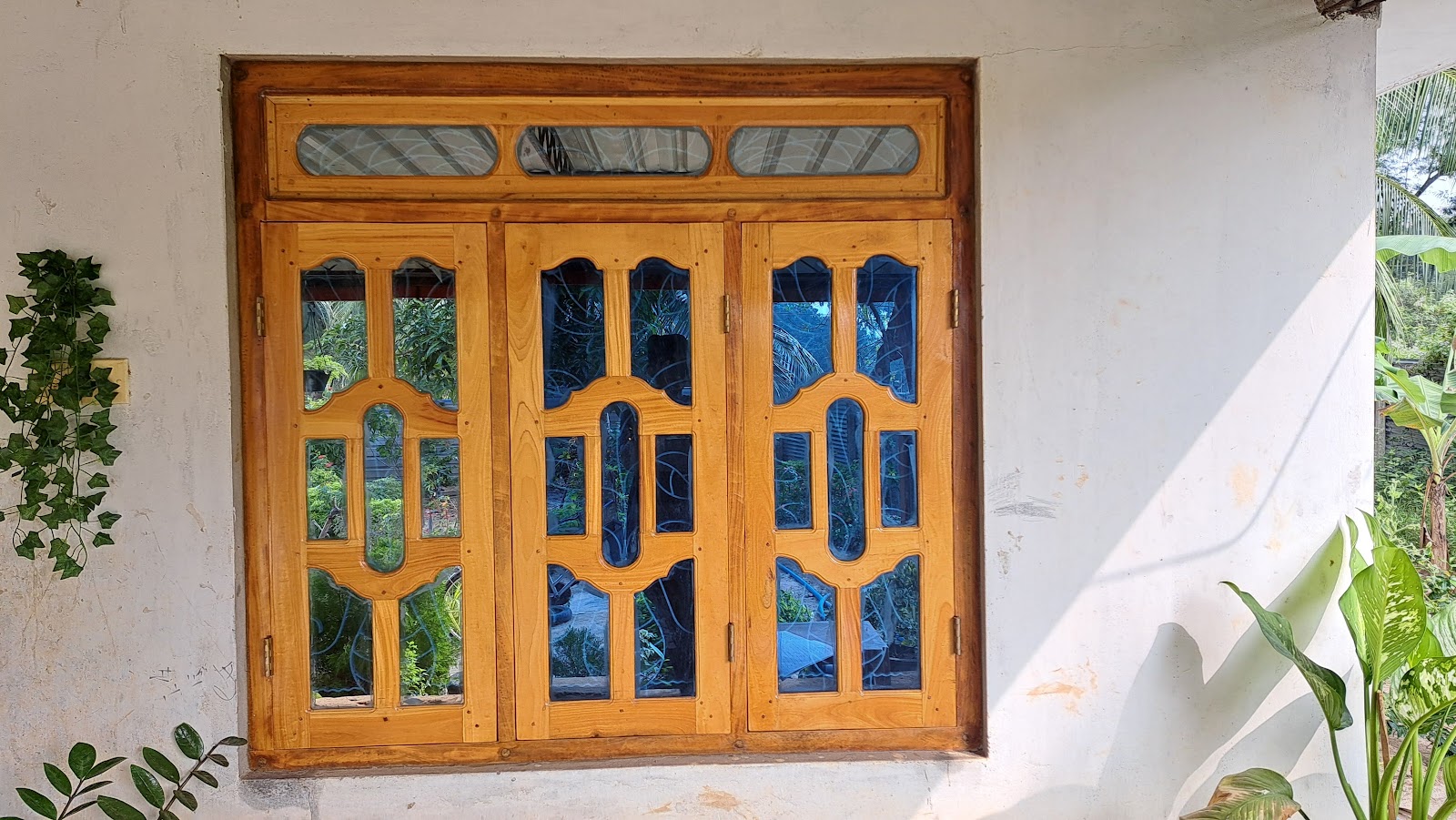 Three-section arched timber window installed in a finished exterior wall
