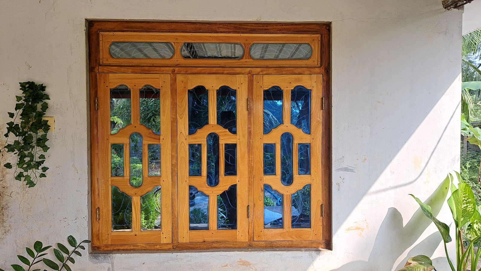 Wide three-section timber casement window with arched glazing details
